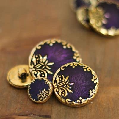 Round resin button with golden metal and byzantin purple