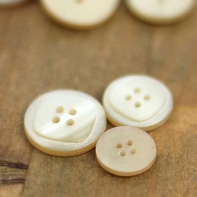 Resin button with pearly aspect