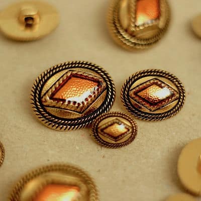 Button with golden metal and amber aspect 
