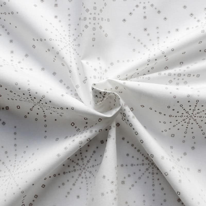 Katoen stof met beige sterrenmotief op witte achtergrond